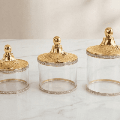 طقم علب تخزين زجاجية بغطاء ذهبي مرصع (بالقطعة). & Glass Storage Jar Set with Gold Embellished Lid (by the piece).