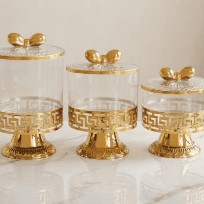 : طقم علب تقديم زجاجية بقاعدة وغطاء ذهبي 3 قطع .  بالإنجليزية: Glass Serving Jar Set with Gold Base and Lid.