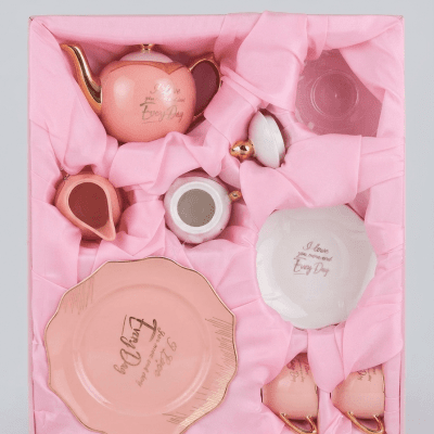 طقم شاي فاخر (24 قطعة) باللون الوردي وتفاصيل ذهبية.  & : Luxury 24-Piece Ceramic Tea Set in Pink with Gold Accents.