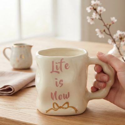 كوب سيراميك يدوي الصنع بعبارة "Life is Now" ونقشة فيونكة ذهبية.  & : Handmade Ceramic "Life is Now" Mug with Gold Bow Accent.