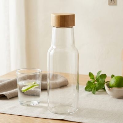 زجاجة أنيقة من الزجاج الصافي بغطاء خشبي طبيعي.. لمسة صحية وعصرية لمكتبك. ✨  ​English: Elegant clear glass bottle with a natural wooden lid.. A healthy, modern touch for your desk